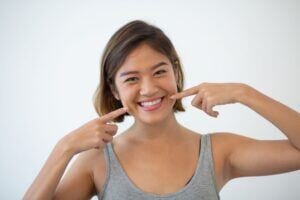 Young woman smiling and pointing to her dimples