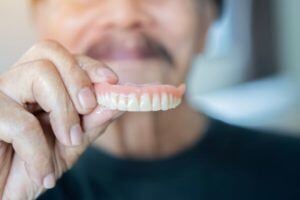 Man holding up top dentures