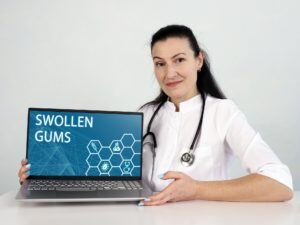 Woman with laptop showing words 'Swollen Gums'