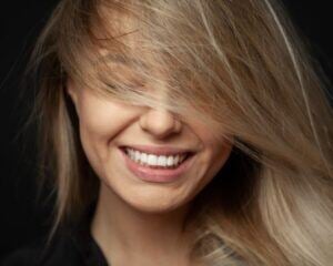 Smiling woman with perfect teeth, hair swept over her eyes