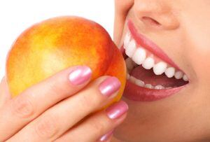 Woman holding peach up to mouth