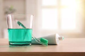 Glass of fluoride next to toothbrush