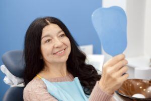 Woman in dentist chair looking in hand mirror